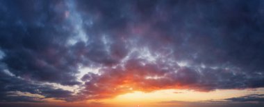 Gün batımında bulutlu gökyüzü. Güneş ufukta batıyor, gri yağmur öncesi bulutlar.