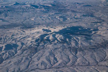 Gökyüzü bulutlu ve dağlar karlı. Fotoğraf bir uçaktan çekildi..