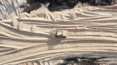İnşaat alanında kum seviyesini yükselten sürüngen buldozerin havadan görünüşü.