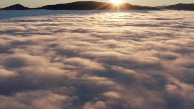 Gün doğumunda yoğun bulutlar ve sislerle dolu resimli bir dağ manzarası. Eğik hava görüntüsü.
