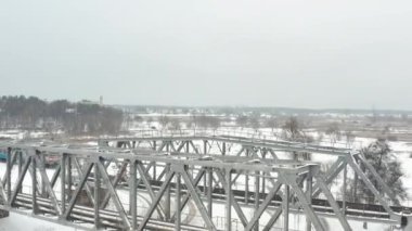 Demiryolu köprüsünden geçen elektrikli banliyö treni kışın karla kaplı..