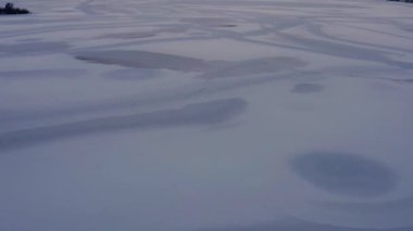 Gün batımında karla kaplı donmuş gölün üzerinde uçmak. Hava karardığında güzel kış akşamının havadan çekimini yapın..