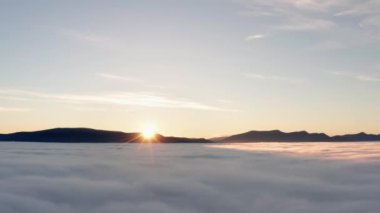 Hava manzarasından gün doğumunda alçak bulutlu güzel bir dağ manzarası. İnsansız hava aracı bulutlara doğru yavaşça uçuyor.