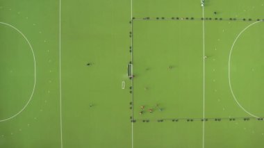Çim hokeyi oyununun hava görüntüsü. Spor sahasında yeşil çimlerle antrenman yapan iki çim hokeyi takımı..