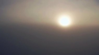 Gün doğumunda dağlardaki bulutların üstündeki yoğun sisin üzerinde kamera yükseliyor. Havadan bakıldığında güzel doğa manzarası.