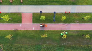 Şafak vakti çim biçme makinelerinin çimleri biçen çim biçme makinesinin üst görüntüsü. Park alanının çimlerinin bakımı.