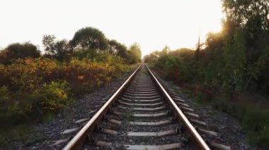 Kırsal kesimde gün batımında tren yolu. Demiryolu üzerinde alçaktan uçan bir İHA..