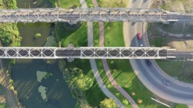 Nehir üzerindeki demiryolu köprülerinin üst hava manzarası ve hareket halindeki arabalarla dolambaçlı yollar..
