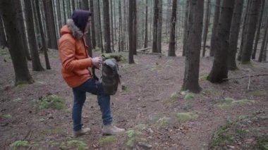 Sırt çantalı genç bir adam dağ ormanında yürüyor. Yürüyüş ve turizm konsepti.