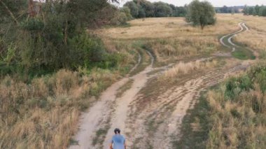 Ağaçlar ve tarlalar arasında kıvrımlı patikalar olan profesyonel bisikletçinin hava aracı görüntüsü. Aktif yaşam tarzı, dışarıda bisiklet sürmek..