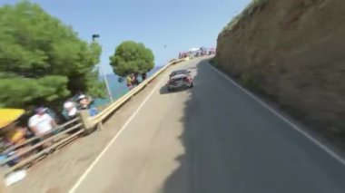 Deniz kıyısındaki uçurum kenarındaki bir arabanın hava manzarası. Güneşli bir günde, neşeli bir kalabalıkla. FPV insansız hava aracı ile filme alındı