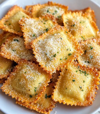 Bir tabak altın sarısı, çıtır çıtır ravioli kareleri üst üste yığılmış mozzarella peyniri ve parmesan peyniri ile ortada. Fotoğraf yukarıdan çekilmiş..