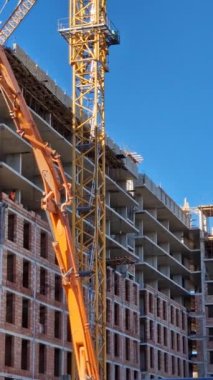 İş sırasında işçilerin ve vinçlerin olduğu bir inşaat alanı. Modern daireler için ev inşa endüstrisi