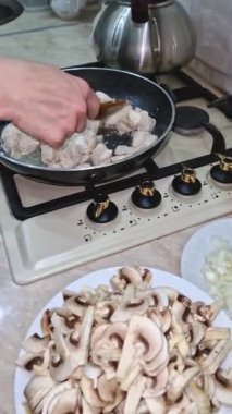 Mutfakta tavada tavuk göğsü kızartan kadın elleri. Dilimlenmiş mantar ve soğan evde lezzetli bir biyolojik yemek hazırlamak için hazır.