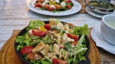 Lokantada yakın yemek tabakları ve ön planda sıcak salata.