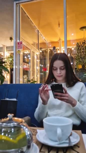 Młoda Kobieta Używająca Telefonu Stojąc Przy Stole Kawiarni — Wideo stockowe