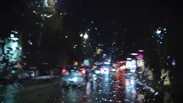 Regentropfen Prasseln Auf Die Windschutzscheibe Eines Autos Verschwommene Außensicht Nachtlichter — Stockvideo