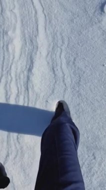 Kış sahnesinde kar üzerinde yürüyen aktif bir adam beyaz kar yığınlarına basıyor.