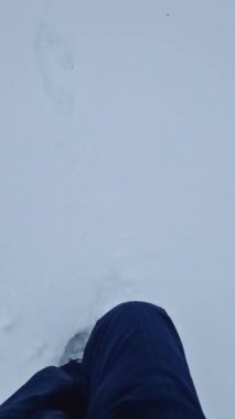 Kış sahnesinde kar üzerinde yürüyen aktif bir adam beyaz kar yığınlarında ayak izleri bırakıyor.