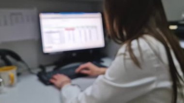 Ofisinde ya da laboratuarında bilgisayar ekranının önünde oturan bir kadının bulanık görüntüsü. Sağlık sektöründe çalışan beyaz üniformalı profesyonel bir kadın doktor.