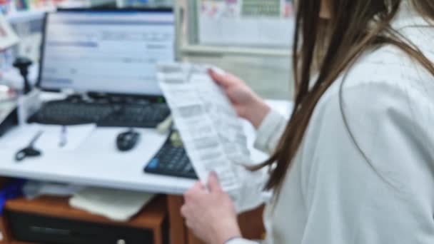 ドラッグストア内で処方箋を読んでいる女性医療従事者の輝かしいシーン 職場の女性薬剤師がバックグラウンドを逸脱 — ストック動画