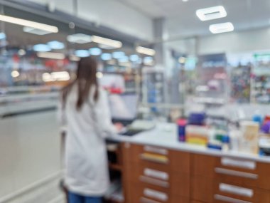 Eczanede, bilgisayarın önündeki tezgahta çalışan kadın eczacının görüntüsü bulanık. Eczaneler ilaç dolu, sağlık endüstrisi bulanıklaştı.