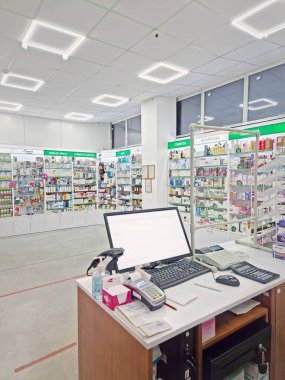 UNGHENI, MOLDOVA - 20 HAZİRAN 2024 Bir eczanenin içinde satıcı tezgahı, bilgisayar ve kasayla stoklanmış raflara karşı ilaç dolu. Sağlık ve kozmetik sektörü geçmişi
