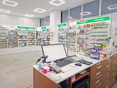 UNGHENI, MOLDOVA - 20 HAZİRAN 2024 Bir eczanenin içinde satıcı tezgahı, bilgisayar ve kasayla stoklanmış raflara karşı ilaç dolu. Sağlık ve kozmetik sektörü geçmişi