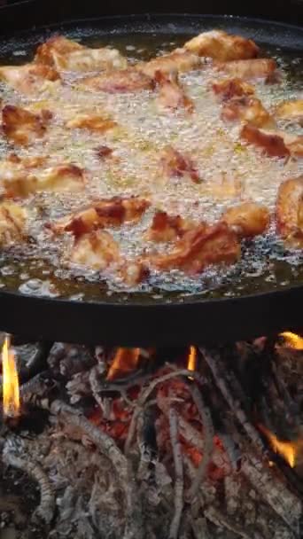 鸡翅在户外的一个大锅子里着火了 沸腾的植物油在火焰下烹调肉类时产生气泡 — 图库视频影像