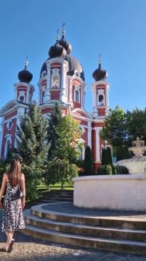 Curchi Manastırı 'nın bahçelerinde çeşme manzaralı genç bir kadın yürüyor. Orhei, Moldova 'da güzel bir yeşil bahçesi olan Hıristiyan Ortodoks Kilisesi