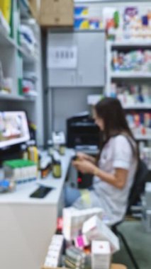 Eczanedeki masada çalışan kadın eczacının geçmişi bulanık, fiyatları belirliyor ve ilaçları depoluyor. Eczane ofisindeki bilgisayarın önünde oturan tıp çalışanı.