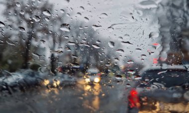 Erimiş kar ve yağmur damlaları arabanın ön camına düşer. Açık hava bulanık, kış mevsimi yağmuru araç penceresinden görülebiliyor.