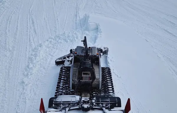 Bulgaristan 'ın Bansko kayak merkezindeki yamaçlardaki kar yığınlarını dengeleyen bir kar aracının hava görüntüsü. Dağlarda kar temizleme makinesi