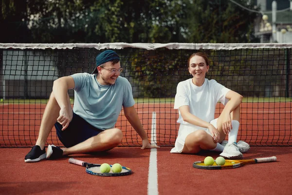 Cheerful Couple Sitting Tennis Court Floor Rackets Ball Friends Smiling — Stock Photo, Image
