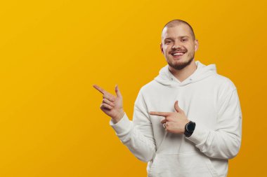 Neşeli adam iki eliyle boş alanı işaret ediyor, reklamlar reklam içeriğiniz için alanı kopyalıyor, sarı arkaplanda izole edilmiş.