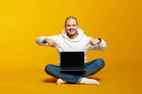 Młody Student Białej Bluzie Kapturem Uśmiecha Się Wskazuje Nowego Laptopa — Zdjęcie stockowe