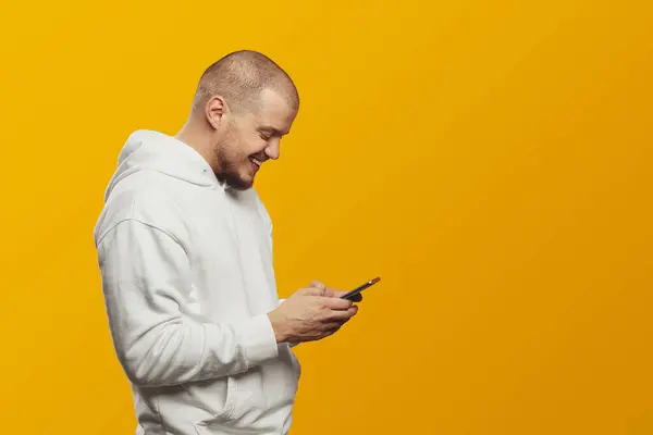 Vista Lateral Jovem Homem Feliz Usando Capuz Branco Usando Telefone — Fotografia de Stock