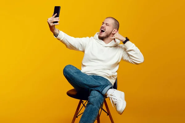Foto Vertical Homem Feliz Sentado Cadeira Usando Smartphone Falando Com — Fotografia de Stock