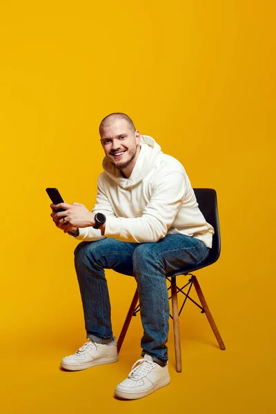 Dobře Vypadající Muž Pomocí Chytrého Telefonu Zatímco Sedí Židli Izolované — Stock fotografie