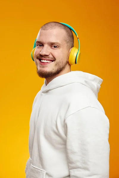 Beyaz Kapüşonlu Sarı Kulaklıkla Turuncu Arka Planda Müzik Dinleyen Mutlu — Stok fotoğraf