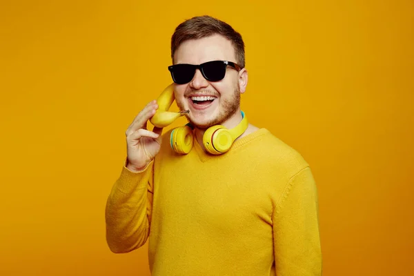 Facet Żółtym Swetrze Okularach Przeciwsłonecznych Słuchawkach Trzymający Świeży Banan Jak — Zdjęcie stockowe