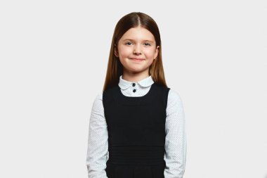 Okul üniformalı heyecanlı kız gülümseyip kendinden emin hissederken sınıfın en iyi öğrencisi olarak beyaz arka plana karşı, okul konseptine geri dönüyor..