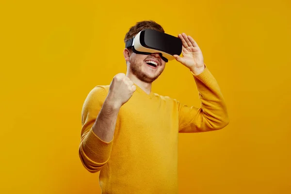 Smiling Excited Young Man Wearing Yellow Sweater Watching Headset Gadget — Stock Photo, Image