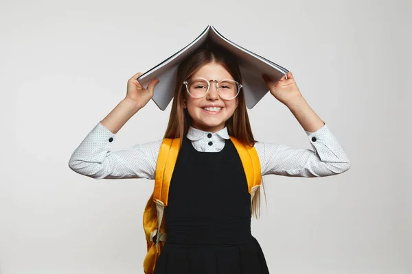 Zabawna Dziewczynka Szkolnym Mundurku Okularach Trzymając Książkę Głowie Patrząc Szczęśliwie Obrazek Stockowy