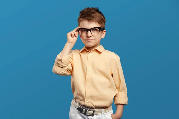 Pequeno Menino Duvidoso Sério Tocando Óculos Olhando Para Câmera Isolado — Fotografia de Stock