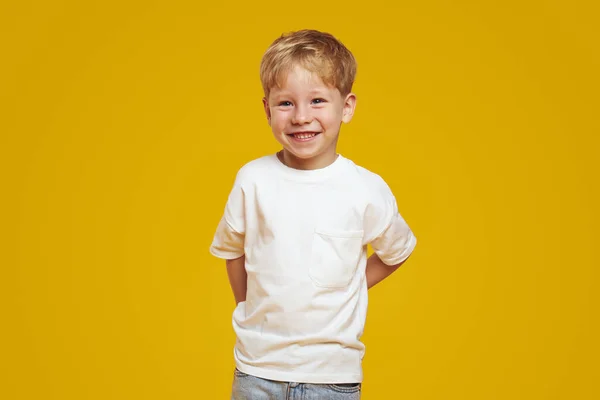 Pozytywny Chłopiec Modnej Białej Koszulce Trzymając Ręce Plecy Uśmiechając Się Zdjęcie Stockowe