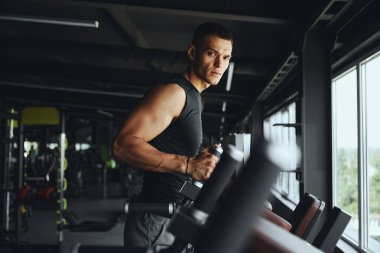 Yakışıklı ve kaslı vücut geliştirici paralel parmaklıklarda duruyor. Gücünü ve dayanıklılığını sınırlarına kadar zorlayacak yoğun ve zorlu bir antrenmana hazırlanıyor.