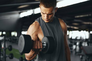 Genç yakışıklı sporcu vücut geliştirici halterci halterciye bakarken dambıllarla halterleri eğitiyor. Vücut geliştirme, fitness ve sağlık hizmeti kavramı.