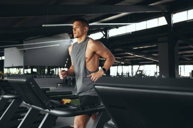 Spor salonunda koşu bandında koşan atletik adamın ısınma turu öncesi rutin egzersizi. Sportif erkek koşu pistinde yürüyor, spor kulübünde sağlık ve spor yapıyor..