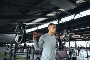 Spor salonunda halterle egzersiz yapan sağlıklı bir genç. Çapraz antrenmanda ağır sıkletlerle antrenman yapan formda bir genç.